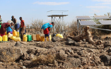 Women in Kenya collecting water next to solar pannels.