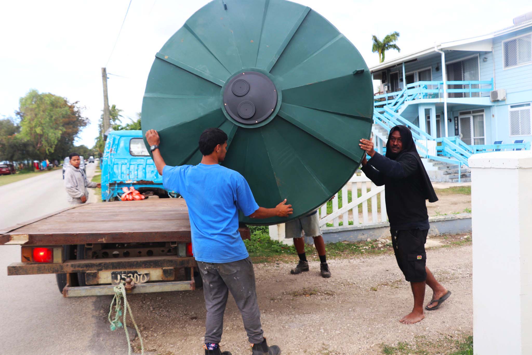 A group of people haul a water tank down from a tuck